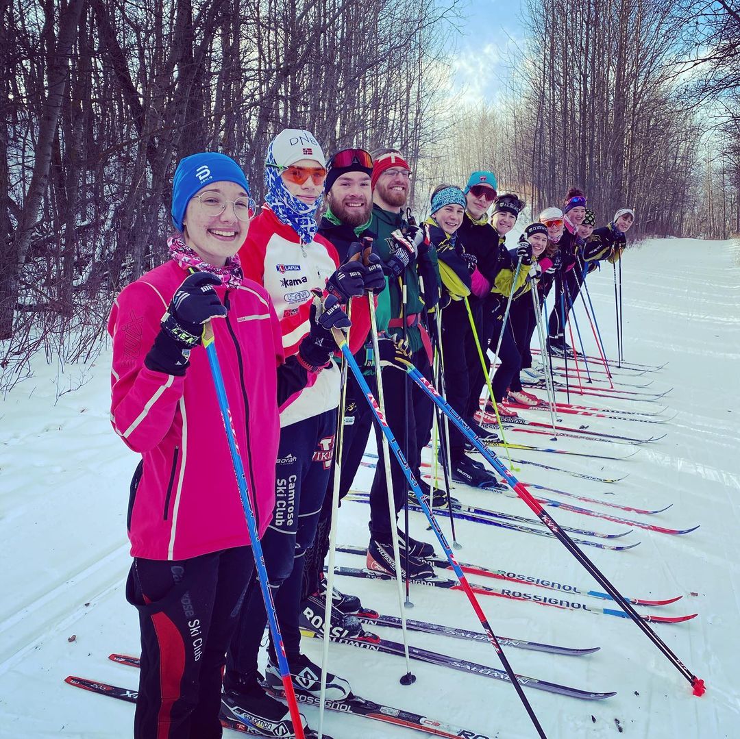 group of cross-country skiers lined up and smiling at the camera